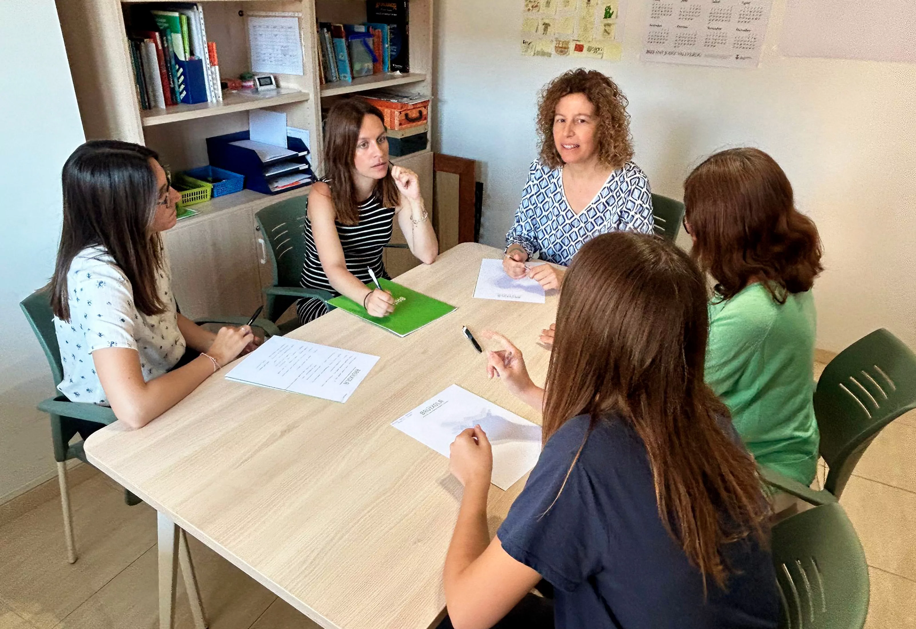Grupo de mujeres en una sesión de terapia en Bruixola Figueres, tomando notas y conversando en equipo