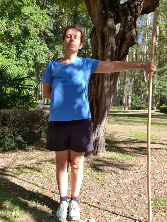 Mujer con los ojos cerrados, sujetando un bastón con un brazo extendido
